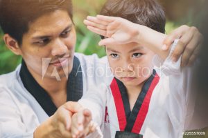 Taekwondo master black belt teaching kid to fight guard