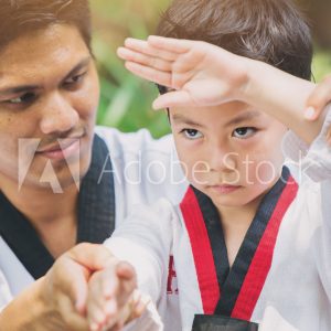 Taekwondo master black belt teaching kid to fight guard